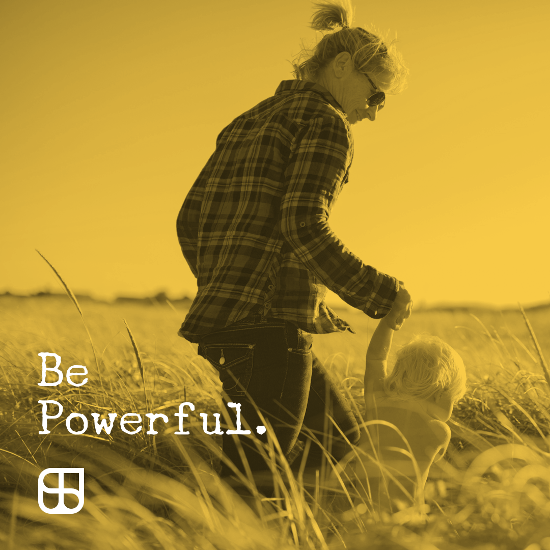 StrongWell social post of a lady holding her baby's hand in a field with the words "Be Powerful" written on it.