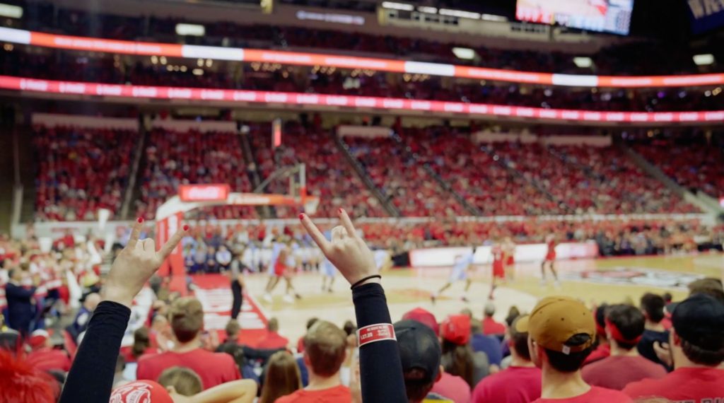 Fan at N.C. State basketball game with Wolfpack hand gesture