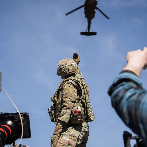 Behind the scenes of an Army National Guard video shoot with a soldier and helicopter