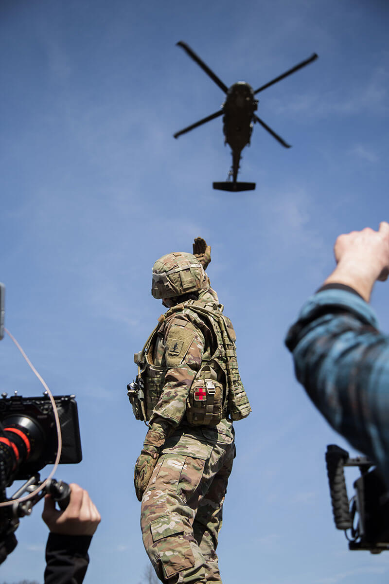 Behind the scenes of an Army National Guard video shoot with a soldier and helicopter