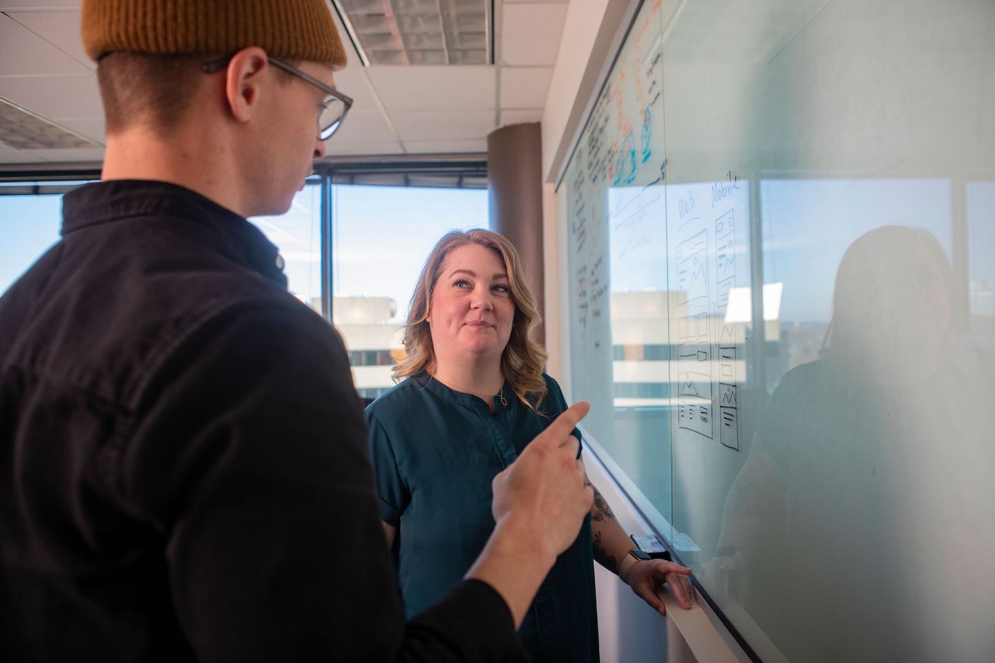 Hayden Zelem and Brandi Leath discussing wireframes on a whiteboard.