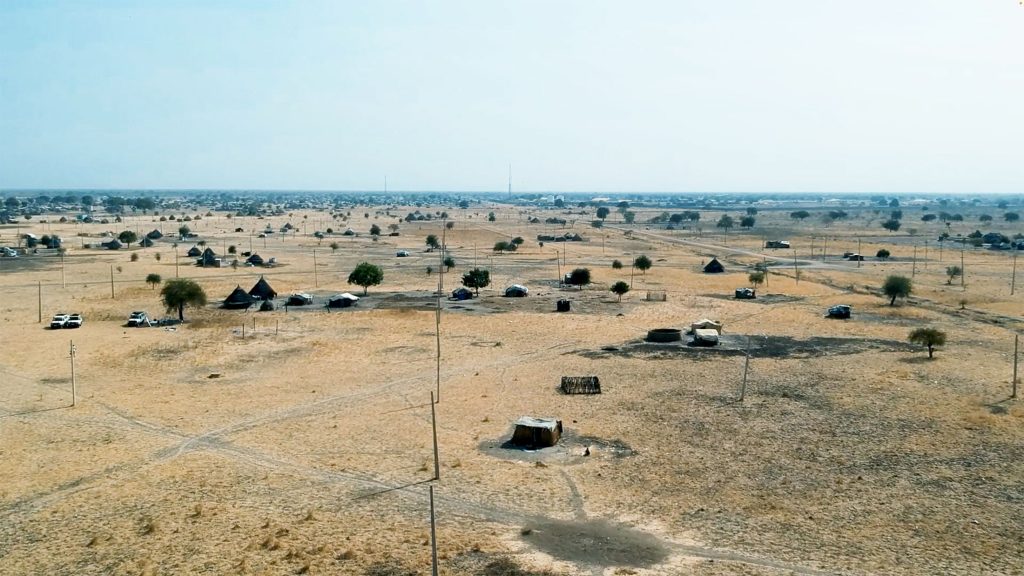 An aerial view of a vast field dotted with numerous small huts, showcasing a serene and rustic landscape.
