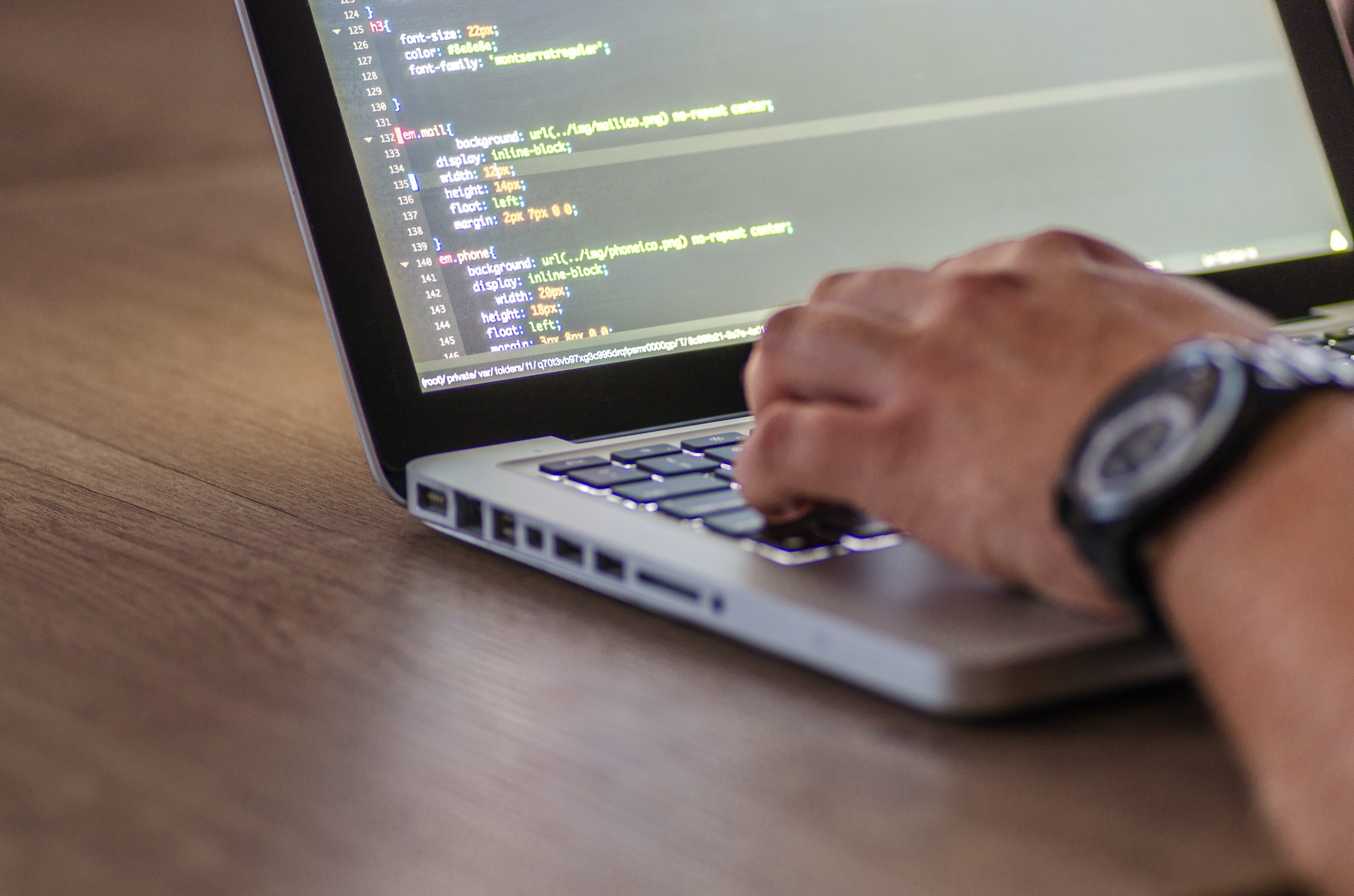 Image of hands coding on a laptop.