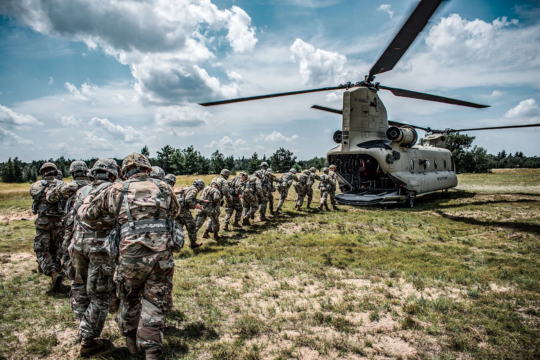 Soldiers walking into a military helicopter in a line.